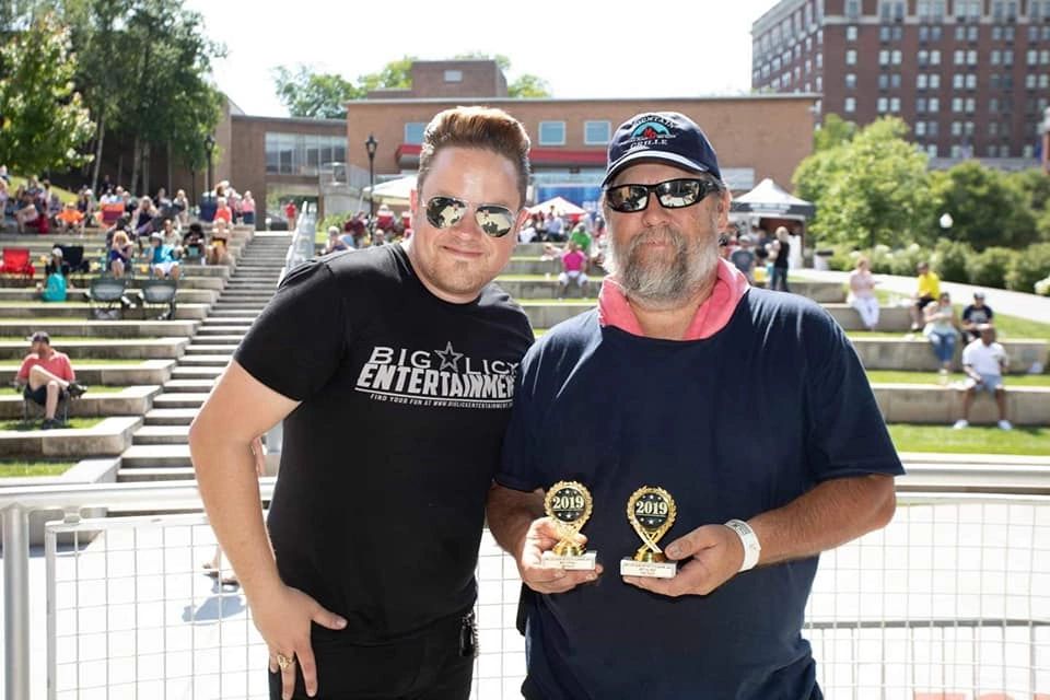 Men holding gold trophies at outdoor plaza
